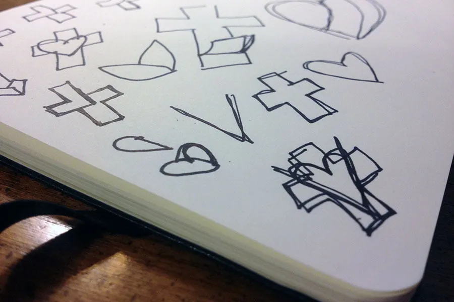 Sketches in a white notebook of the new logo icon for the business. 
