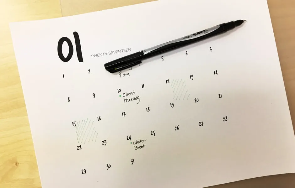 The January calendar printable with a thin-point sharpie laying on top. The calendar has writings on it. 