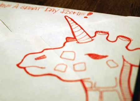 The back of the envelope has a drawing of a red giraffe on it. The top says, "Have a great day roomie!"