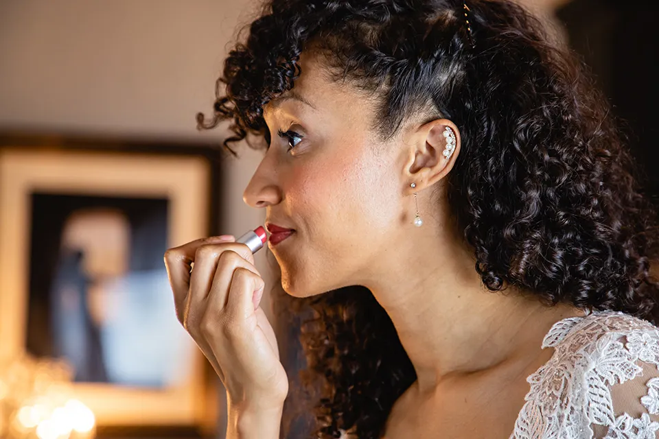 The bride applies red lipstick in the mirror in the bridal suite. 