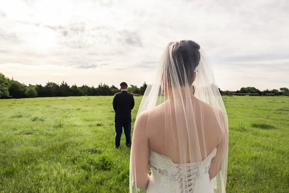 The bride stands several feet behind the groom. His back is toward her and they get ready to have their first look. 