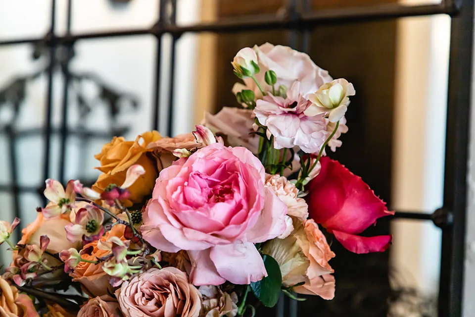 An up-close shot of the bride's wedding bouquet, which includes pink and orange roses. 