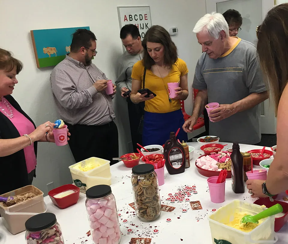 A small group of clients chat while getting ice cream at the ice cream social. 