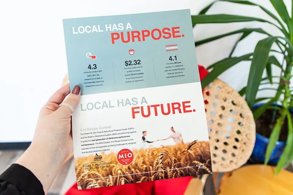 Improve Content Engagement through Design - myheartcreative A hand holds a brochure card for the MIO Coalition. The graphic brand design OKC utilizes content effectively. Two headers read, "Local has a purpose." and "Local has a future."