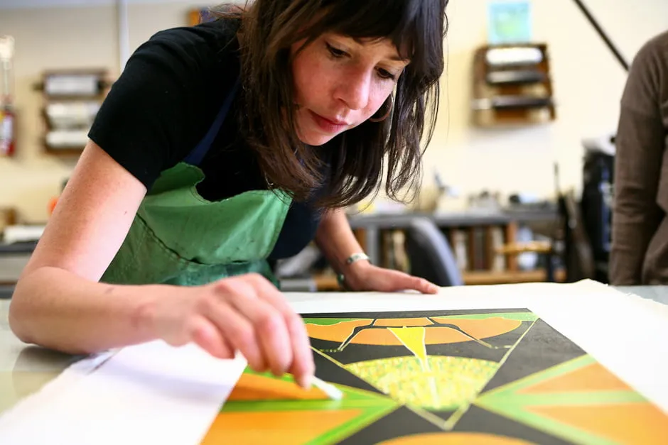 Make work. - myheartcreative A female artist wears a green apron while finishing up a colorful abstract painting.
