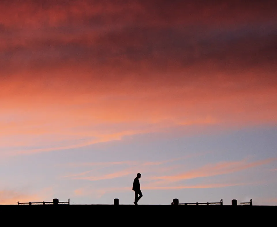 Think Differently - myheartcreative A silhouette of a man walking down a street with a pink sunset as the background.