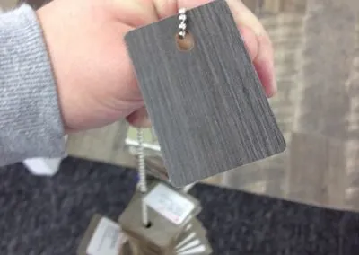 The Creative Director holds a dark grey wood sample for the design studio's new flooring.