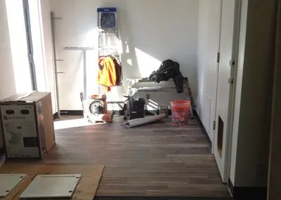 A paint-covered ladder and work bench rest along the back wall of the studio next to the back door.