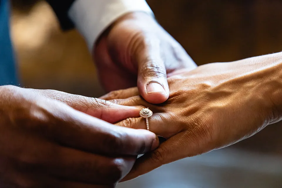 The groom places a diamond wedding ring on the bride's ring finger. 