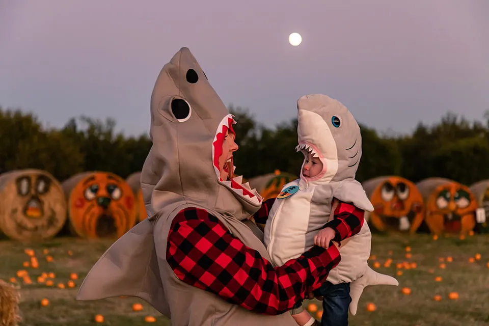 Looking Back on a Year of Web Design OKC - myheartcreative A mom wearing a shark costume smiles at her baby wearing a small shark costume. They are at a pumpkin patch, and the moon shines brightly behind them.