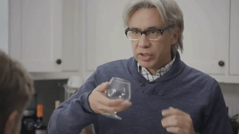 A gif showing a man swirling a small glass of wine. 