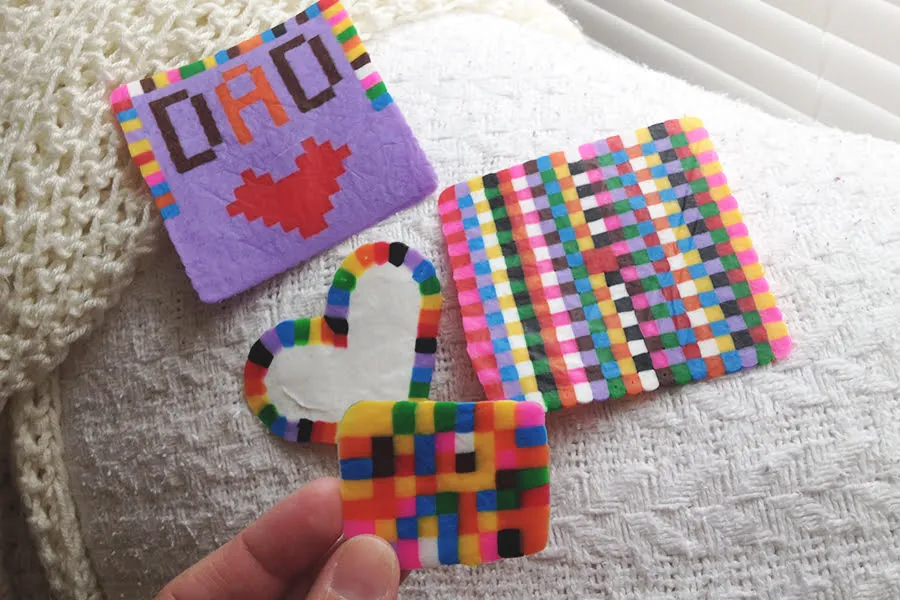 Melted bead artworks. One is in the shape of a heart, two are shaped like squares, and one is a square with a red heart and "DAD" above it. 