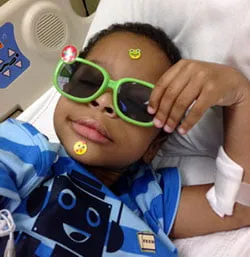 Be the change. - myheartcreative A young boy names Jayden lays in a hospital bed. He has stickers all over his face and wears neon green sunglasses.