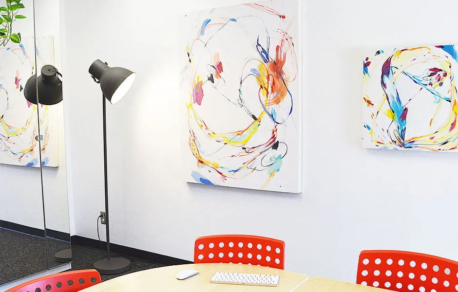 Space Altering Creator - myheartcreative Two abstract paintings by Katelynn Noel Knick hang on the conference room wall next to a tall black lamp.