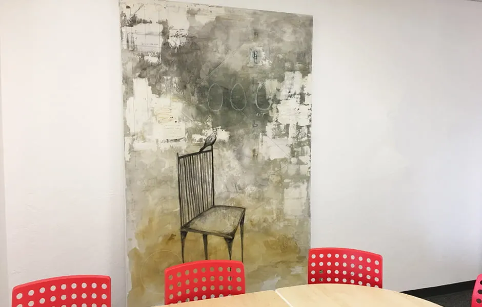 A large abstract painting by Brandi Downham. The painting shows a chair with a bird sitting on the tip edge of it. 