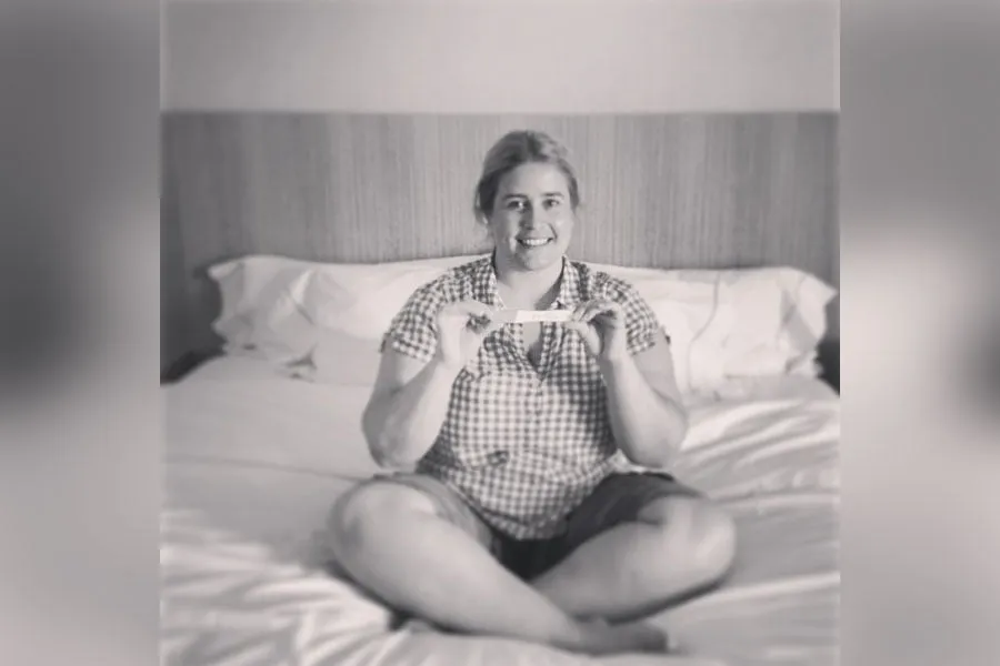 Amy holds a positive pregnancy test for baby Koraline. 