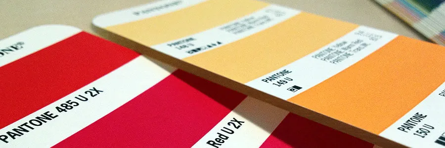 Two pantone chips, one with red colors and one with orange colors. 