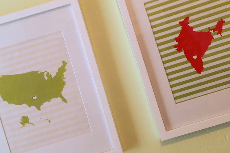 Two pictures hanging on the yellow wall of Maximus's nursery. One has a green image of the United States with a heart cut out in the Oklahoma area. The second has a red image of India with a heart cut out in the Bengaluru area. 