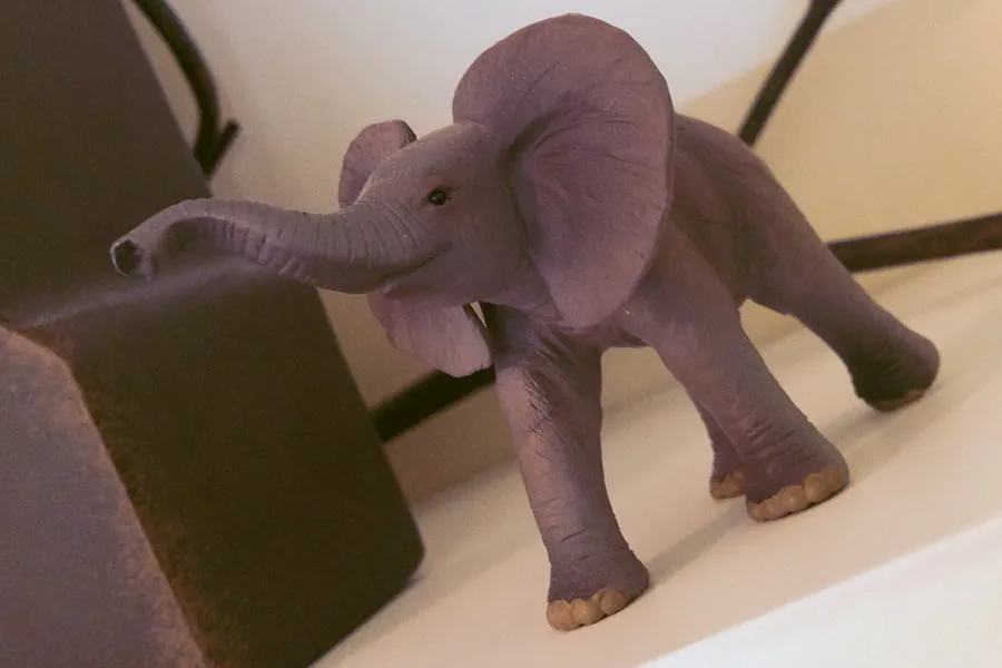 A small figurine of an elephant on a shelf. 