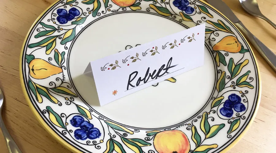 A Thanksgiving name card sitting on a plate. 