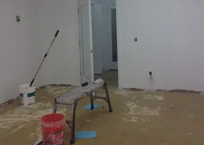 A paint-covered bench sits next to buckets of paint in the soon-to-be conference room.