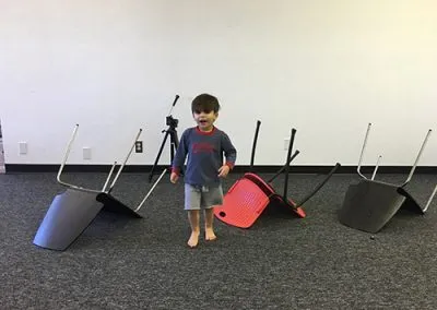 Sam and Amy's son Maximus runs between toppled-over chairs on the studio's new black carpet.