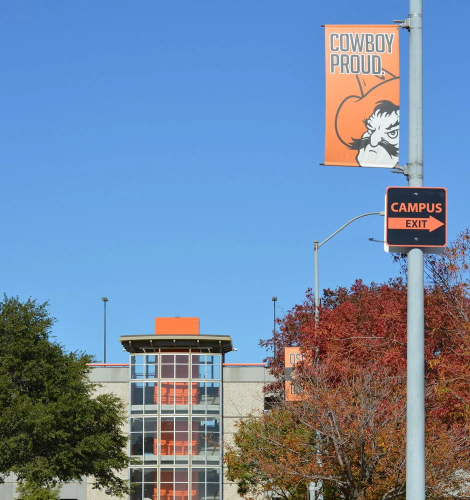 A pole banner on the OSU OKC campus. The banner reads "Cowboy Proud" with the OSU cowboy mascot below it. 