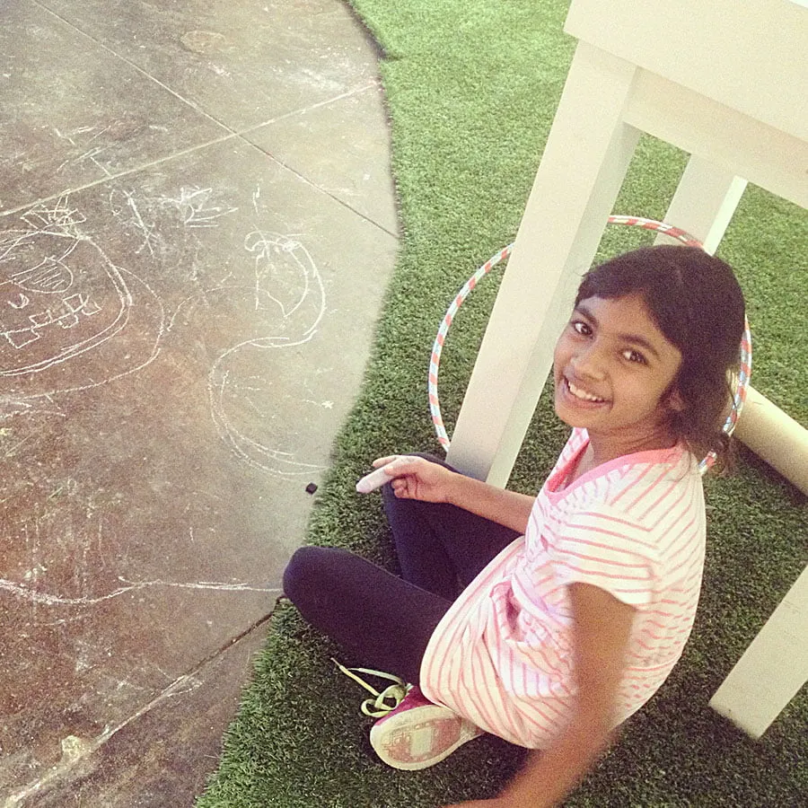 Kaitlynn draws on the ground with purple chalk. 