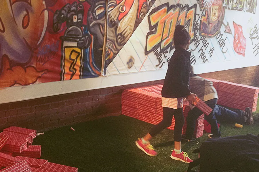 Katelynn, a young girl, and a young boy play with foam bricks in a creative play space in OKC. The walls are covered in creative graffiti. 