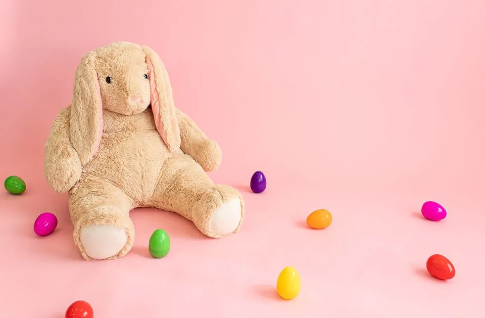 Capture Precious Memories with OKC Photography - myheartcreative A stuffed bunny with various multi-colored plastic Easter eggs surrounding it on a pink background. The set-up is for an Oklahoma mini photoshoot.