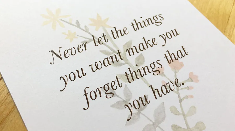 A Thanksgiving plate card that says, "Never let the things you want make you forget things that you have." 