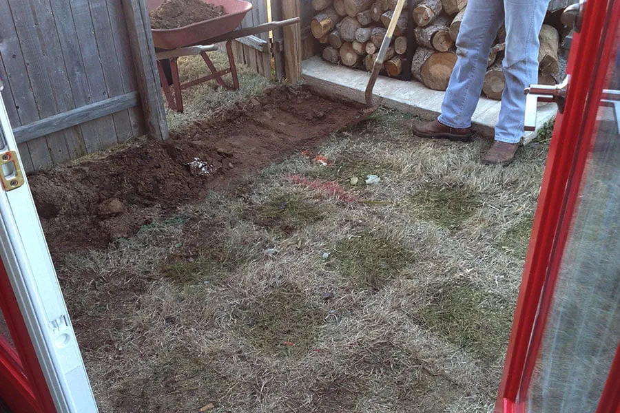 A man digs up grass to prepare for cement. 