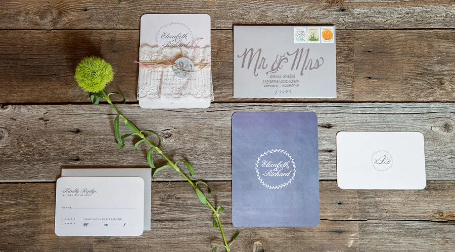 Styled Stationery - myheartcreative A flat lay of styled wedding stationary. The flat lay includes a custom-designed wedding invitation, response card, and envelope. There is a piece of greenery laying amongst the stationary.