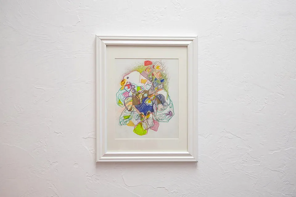 An Artistic View - myheartcreative A colorful abstract painting by Mycah Higley in a white frame hangs on the myheartcreative studio walls.