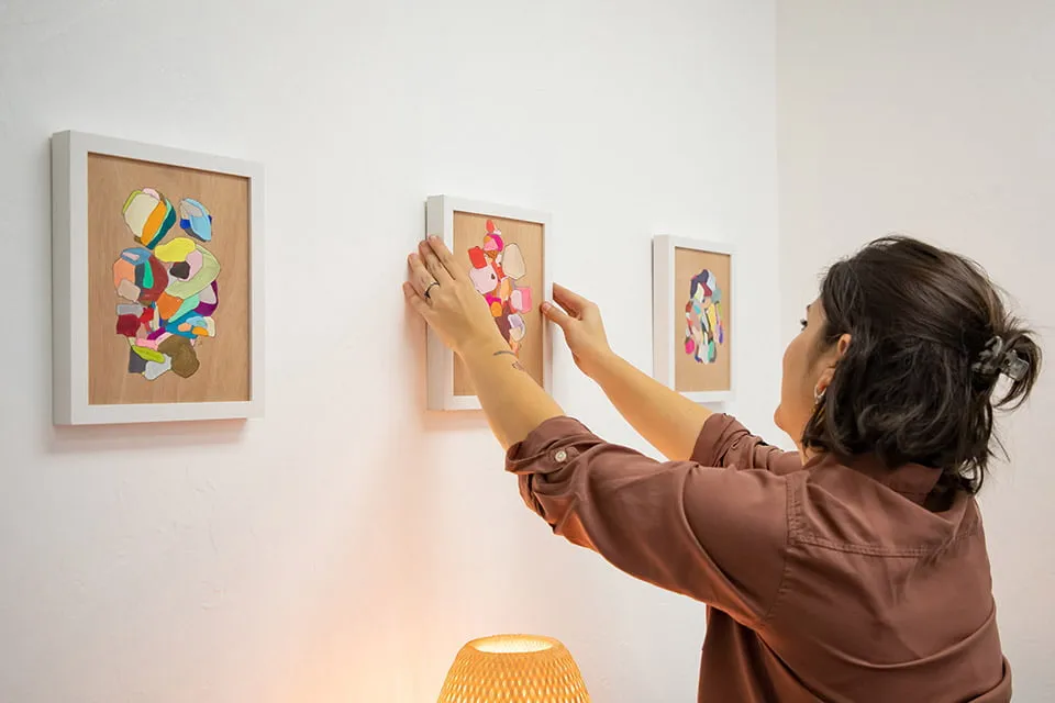 An Artistic View - myheartcreative Artist Mycah Higley adjusts the middle art piece on a gallery wall at the studio.