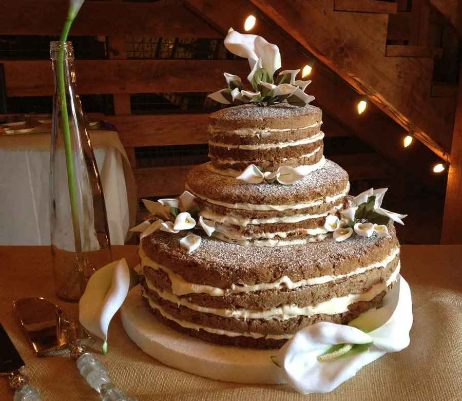 The Thompson's wedding cake. It is a three-tiered naked wedding cake with white flowers all around. 