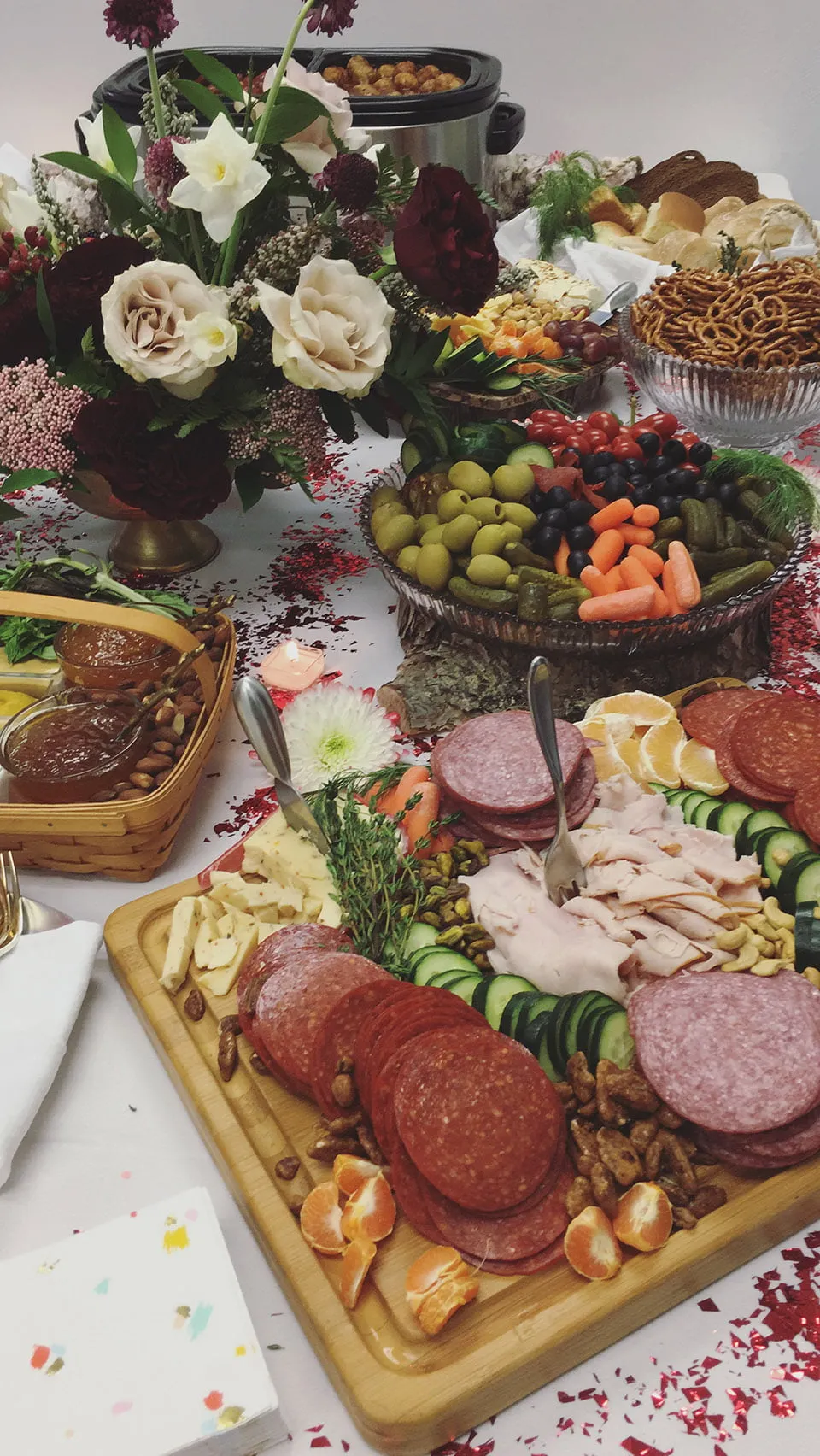 The myheartcreative conference room table transformed for the client appreciation party. There are charcuterie boards, fruit trays, and other snacks surrounding a beautiful flower arrangement. 