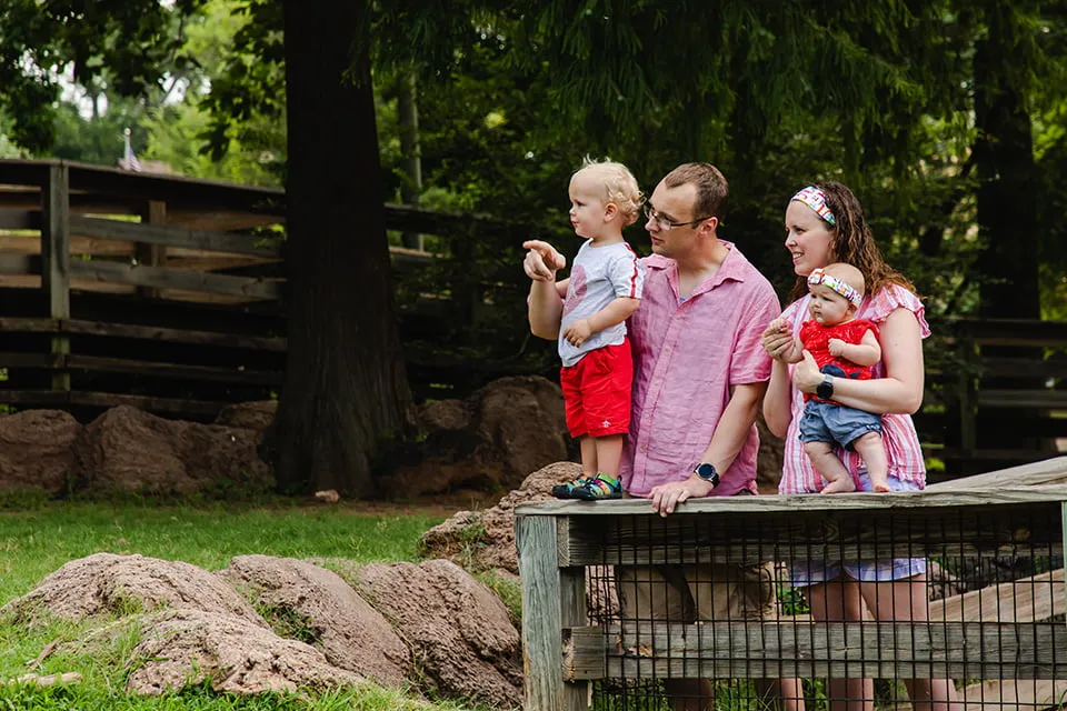Looking Back on a Year of Web Design OKC - myheartcreative A dad holds his toddler and points to animals at the zoo while the mom watches holding a baby girl.