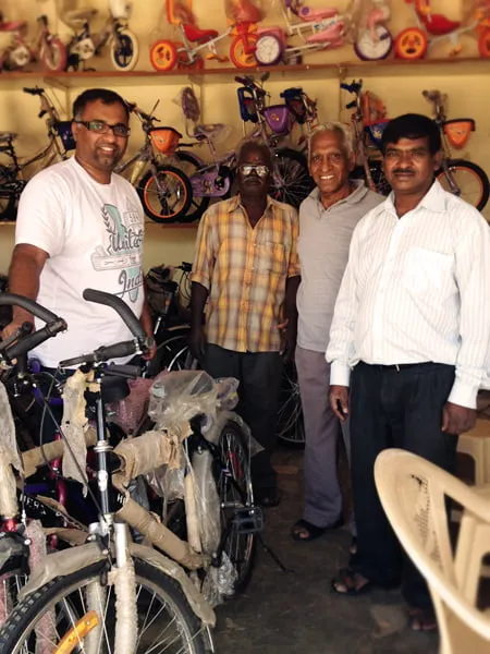 Sam stands with three men at a bike shop in India. 