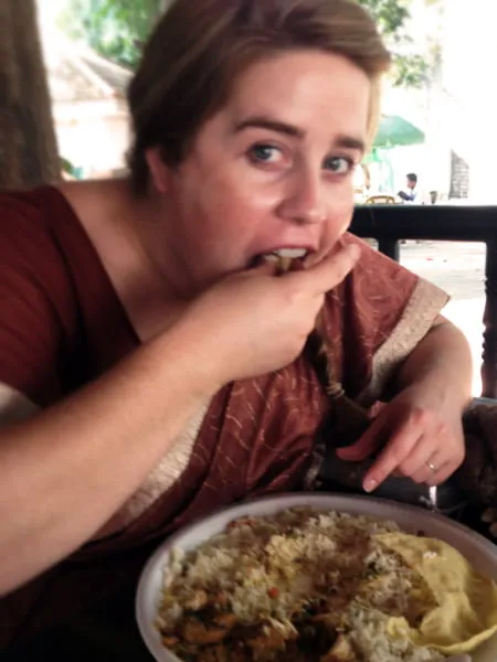 Amy eats traditional Indian food while wearing a sari. 