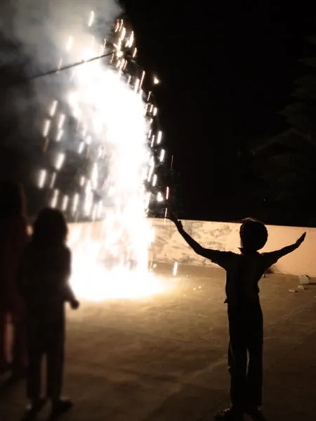 A young boy raises his arms in amazement at fireworks. 
