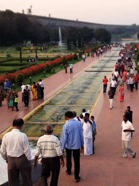 Crowds of people walk around a reflection pool at an attraction in India. 