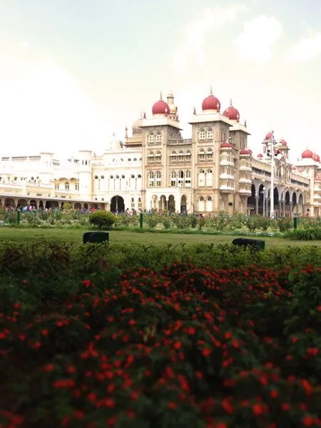 A large building in India with a green field surrounding it. 