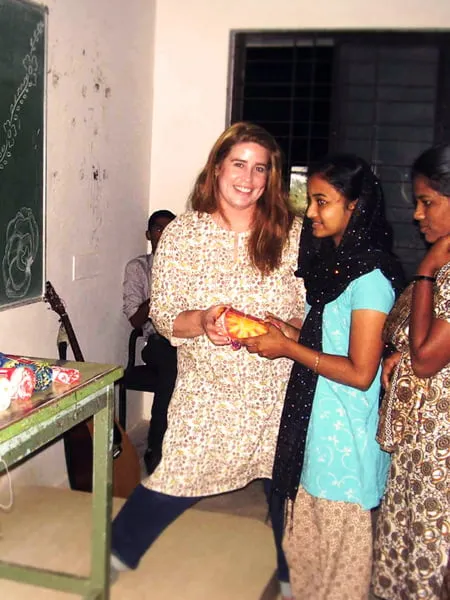 Amy hands a young Indian girl a snack. 