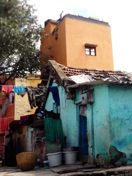 A small turquoise blue home in India. There are clothes drying in a clothes line. 