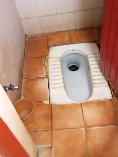 A toilet in the ground in India. 