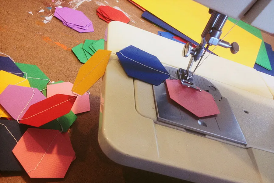 A homemade colorful garland being sewn together by Amy. 