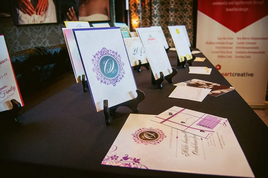 A table with various invitation designs by myheartcreative on display. 