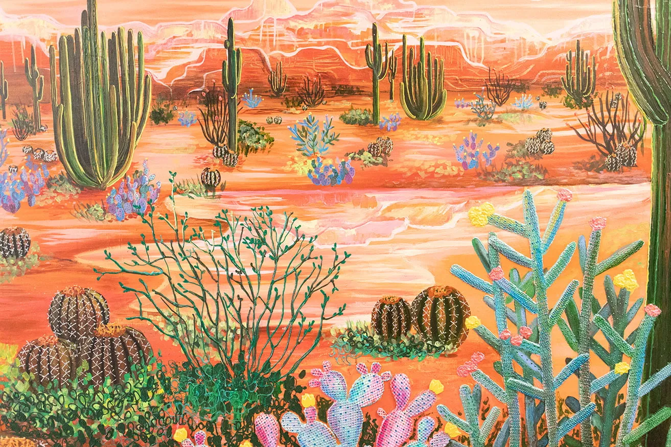 A large painting of a desert landscape and flora by artist Kyndall Rainey. 