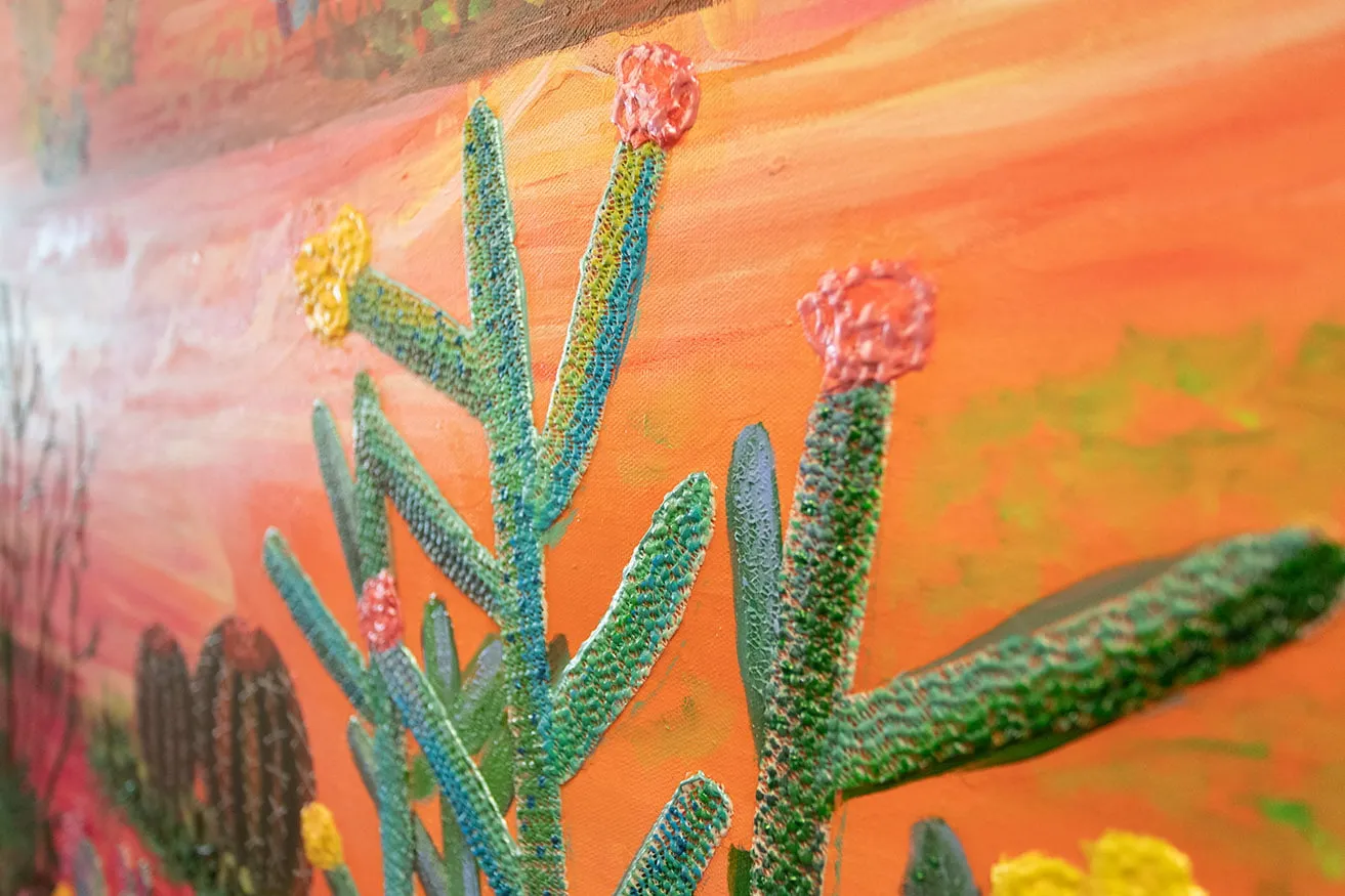 A up-close shot of a cactus painted on an orange sunset background by Kyndall Rainey. 